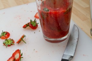 muddling the strawberries in the cocktail glass