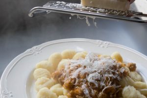 Adding Parmesan to sausage ragu and gnocchi